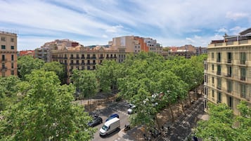 A cityscape with multi-story buildings, a street with vehicles, and trees lining the road.