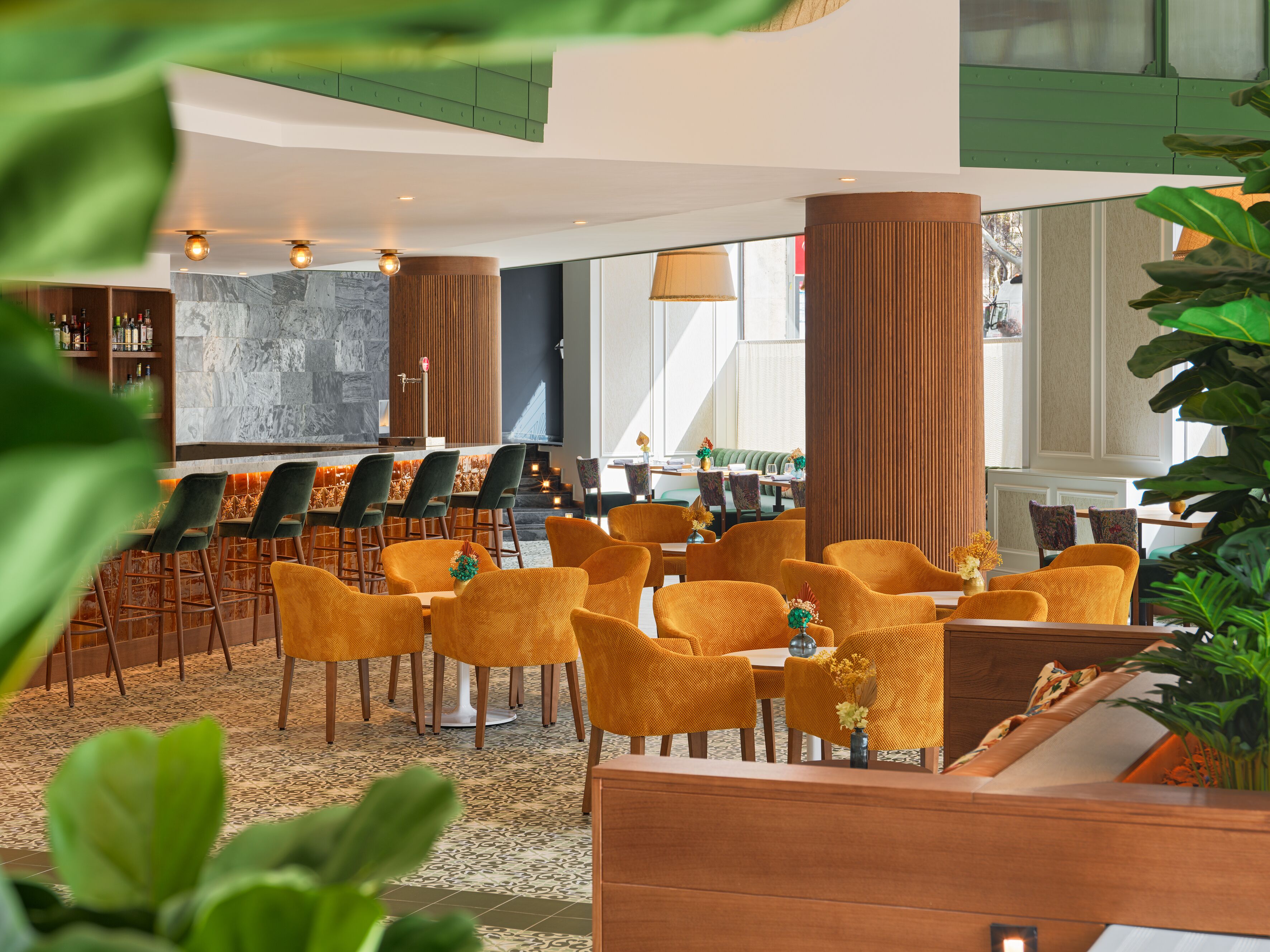Un moderno vestíbulo de hotel con área de bar, zonas de estar y amplios ventanales que dejan entrar luz natural.