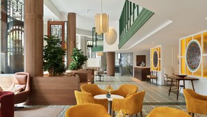 A spacious lobby with a central seating area, large columns, and a staircase leading to upper floors. - H10 Casanova (Barcelona)