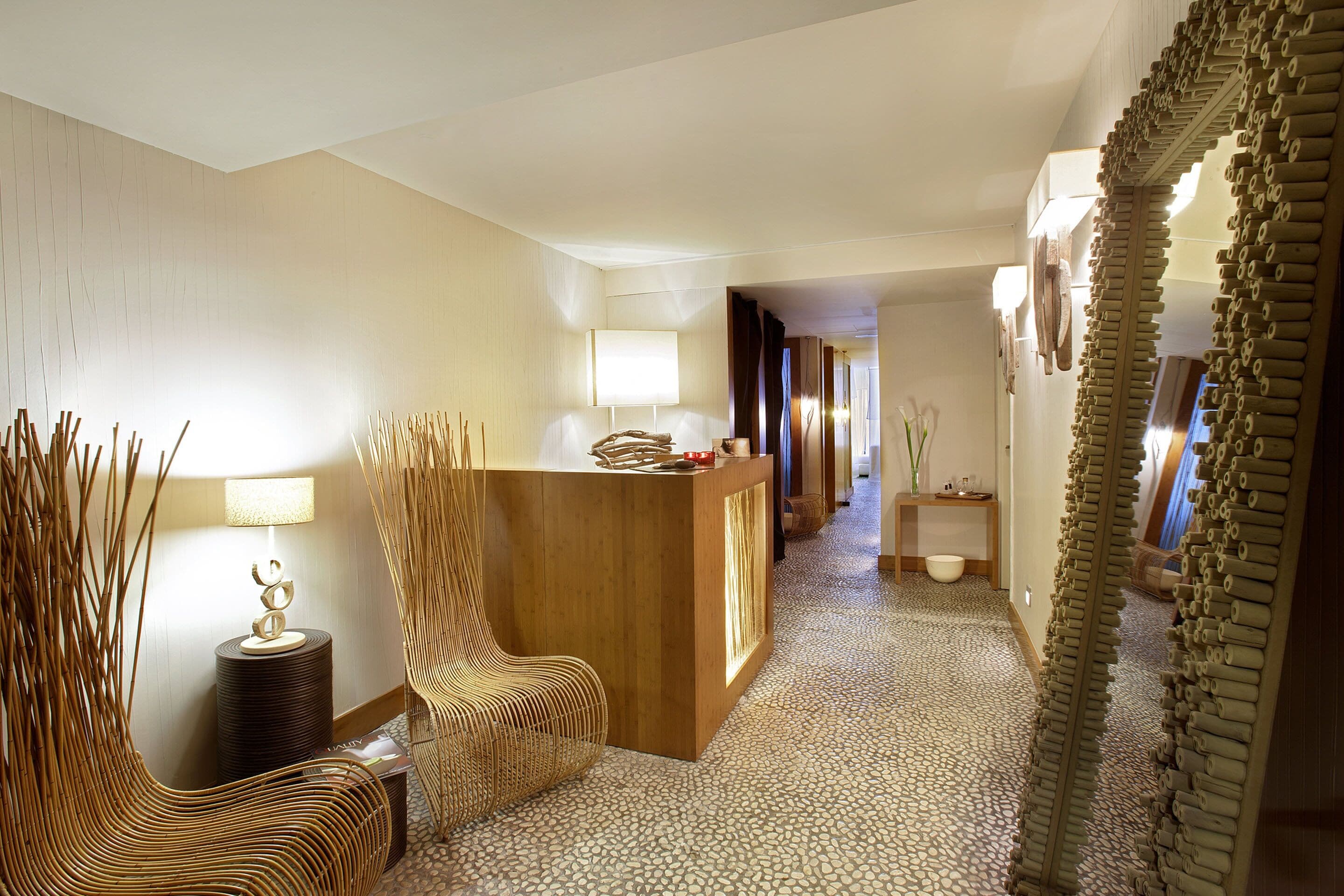 A reception area with a wooden desk, a chair, a lamp, and a decorative mirror.