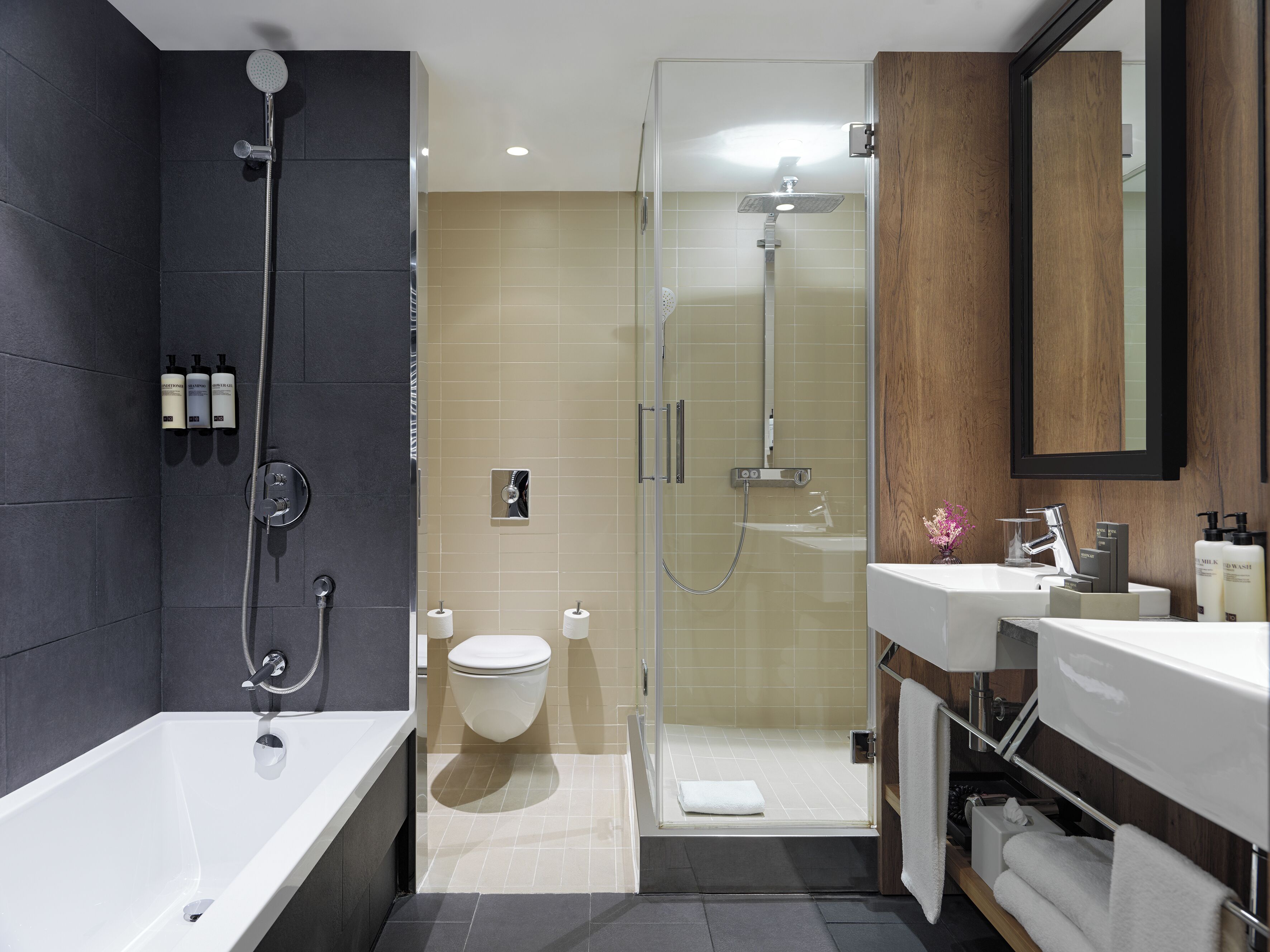 Un baño moderno con bañera, ducha con mampara de vidrio, inodoro y tocador con espejo.