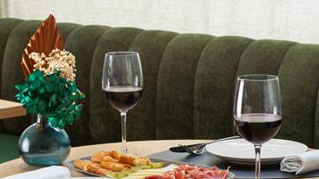 Una mesa con platos de comida, dos copas de vino y un florero con flores.