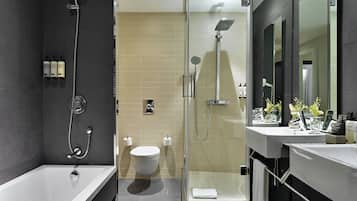 Une salle de bain moderne équipée d’une baignoire, d’une douche à parois de verre, de toilettes et d’un meuble-lavabo avec un miroir.