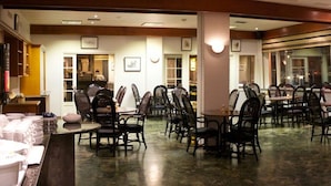 A restaurant with multiple tables and chairs, a marble floor, and framed pictures on the walls.