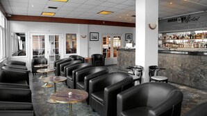 A bar area with leather seating, a bar counter with various bottles, and a stone wall.