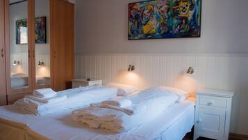 A hotel room with two beds, a large mirror, a painting on the wall, and a nightstand with a lamp.