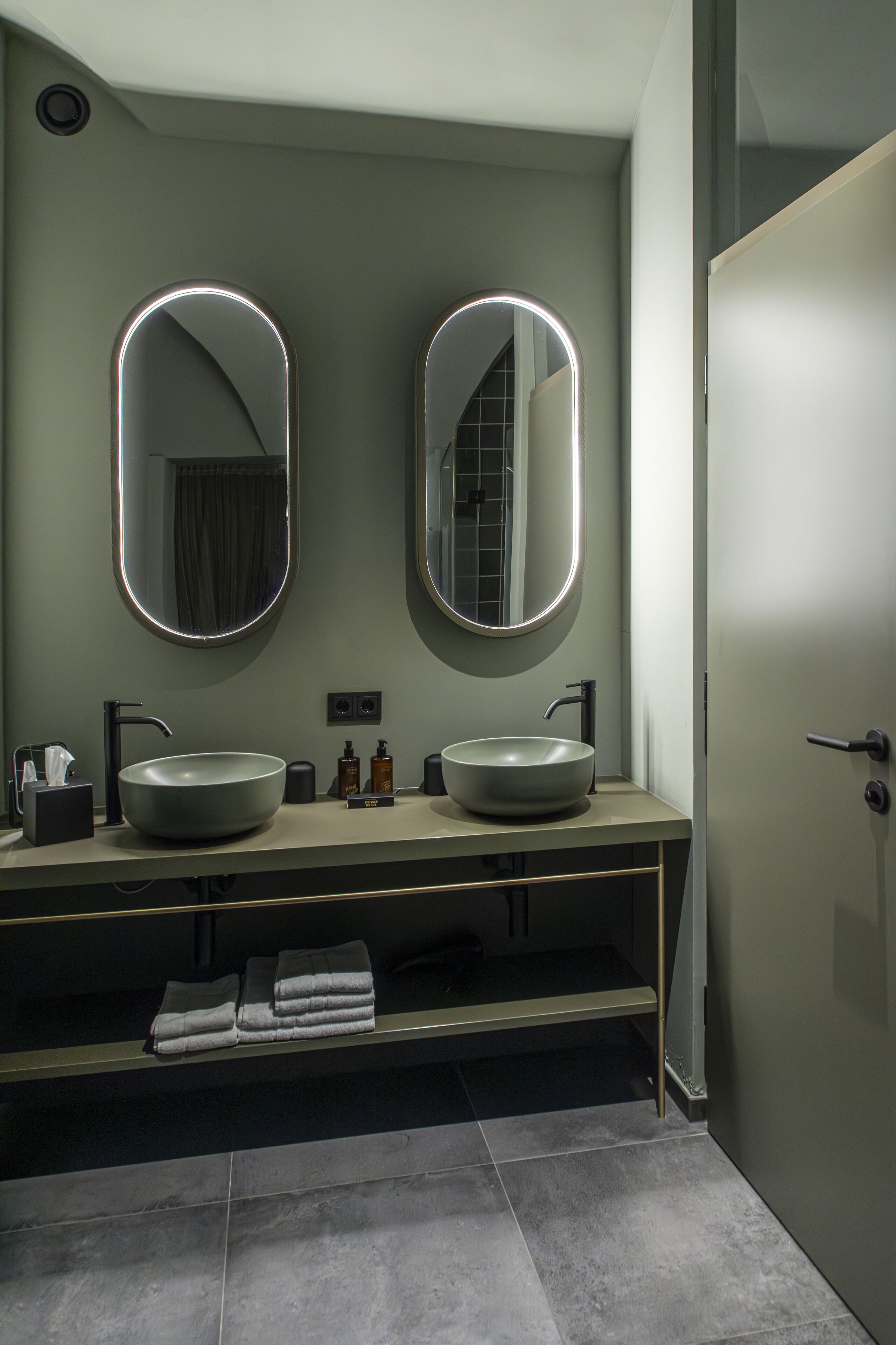 A modern bathroom with two round mirrors, a double sink, and a towel rack.
