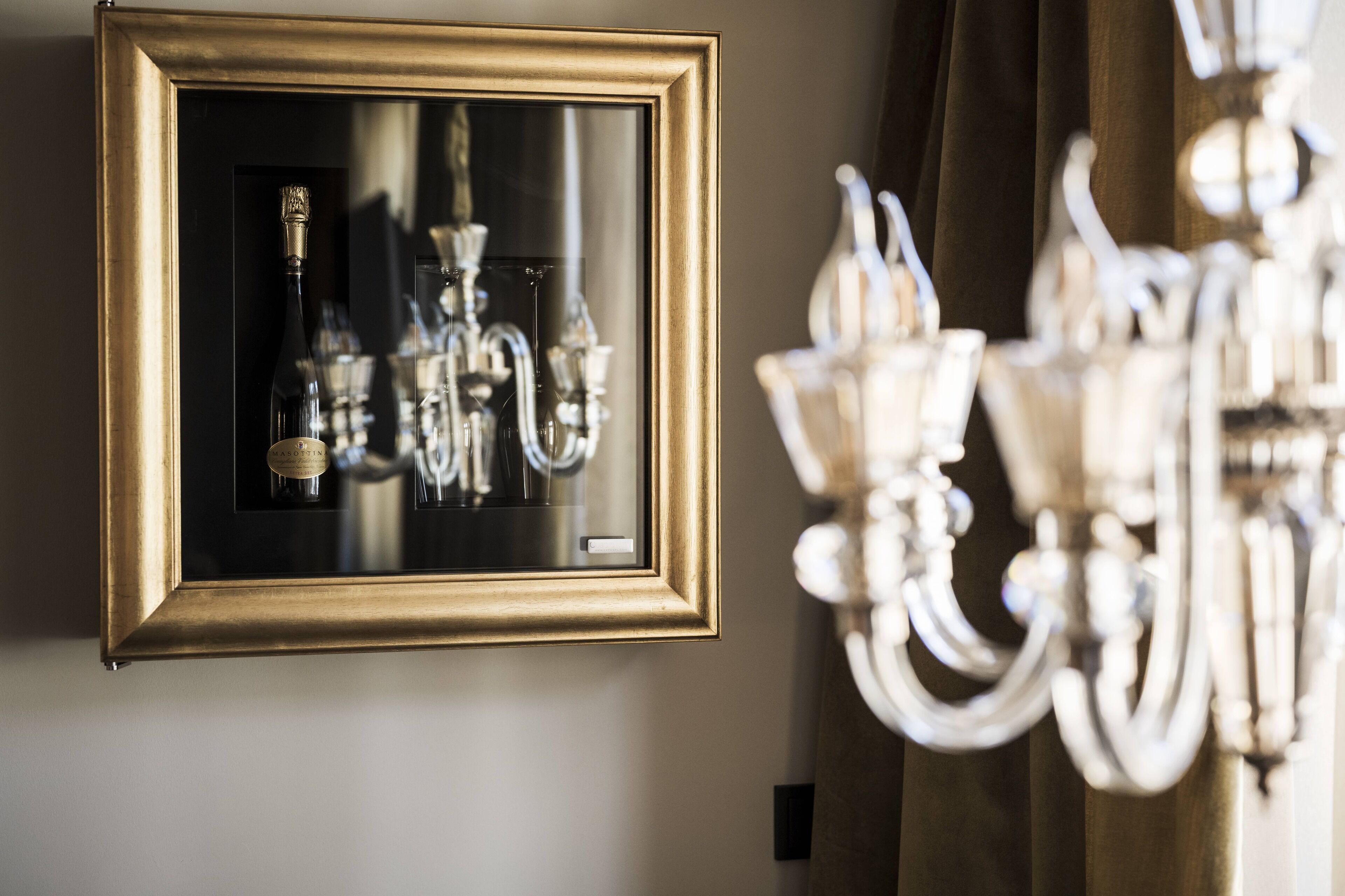 Espejo en marco que refleja un candelabro y botellas de vino.