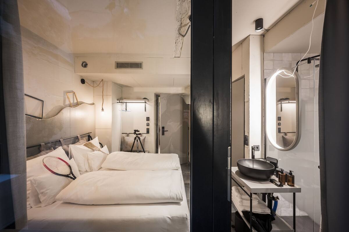 Habitació d'hotel moderna amb un llit gran, una tocador amb un lavabo i un mirall.