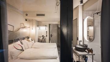 Una habitación de hotel moderna con una cama grande, un tocador con lavabo y un espejo.