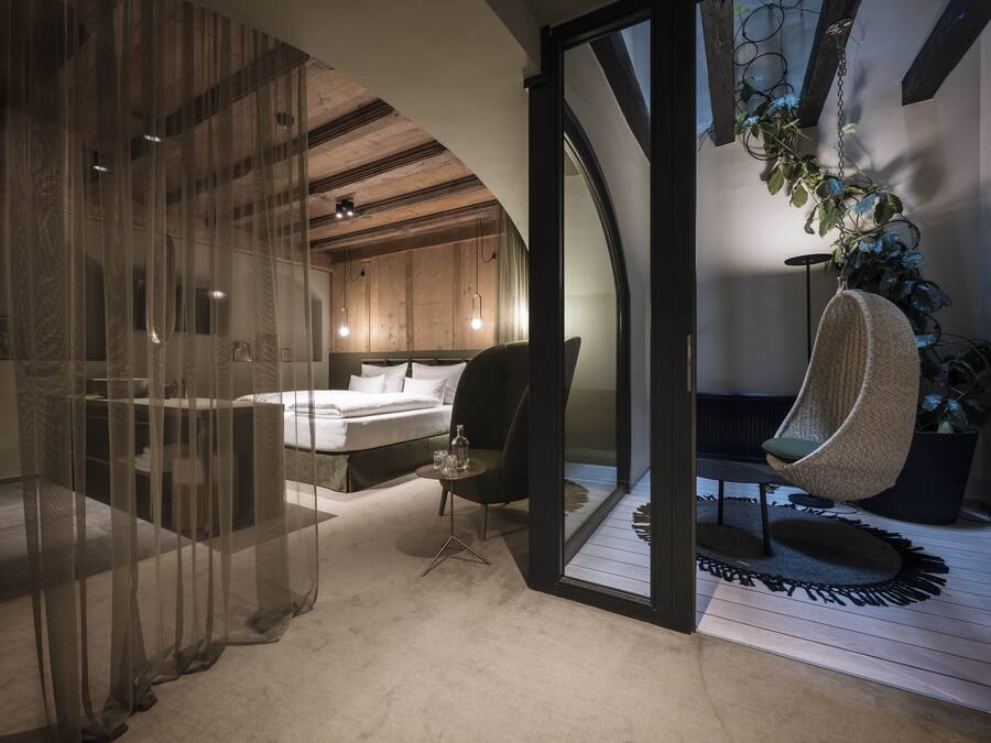 Une chambre à coucher moderne avec un lit, une chaise et une plante suspendue.