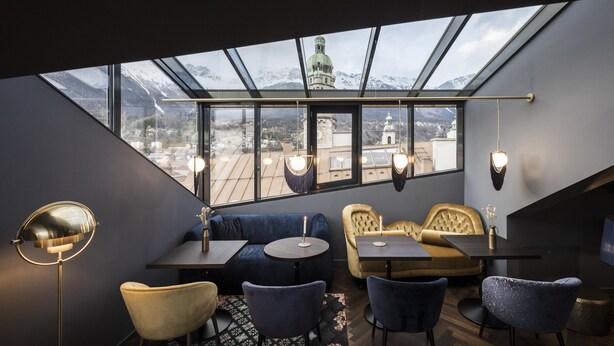 A modern interior with a skylight, seating area, and a view of snow-capped mountains.