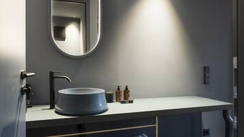 A modern bathroom with a round mirror, a sink, and a towel rack.