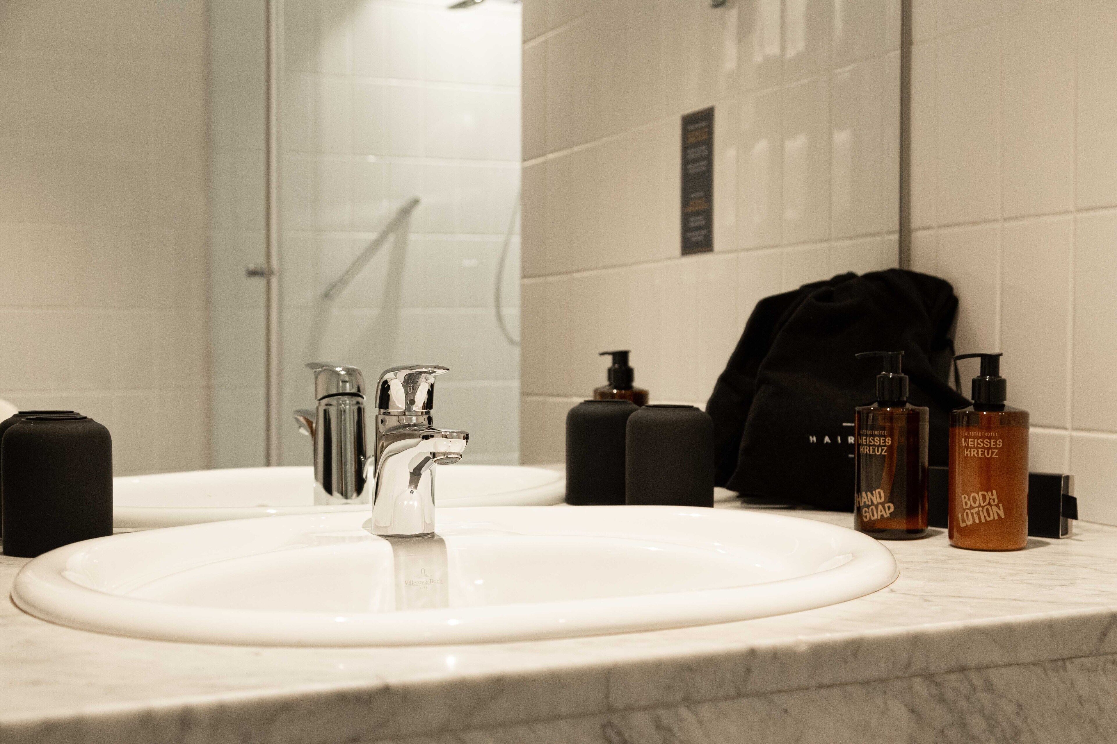 Un baño con lavabo, espejo y artículos de aseo.