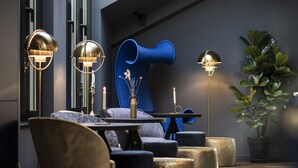 A modern interior with a dining area, a blue curved wall, and a potted plant.