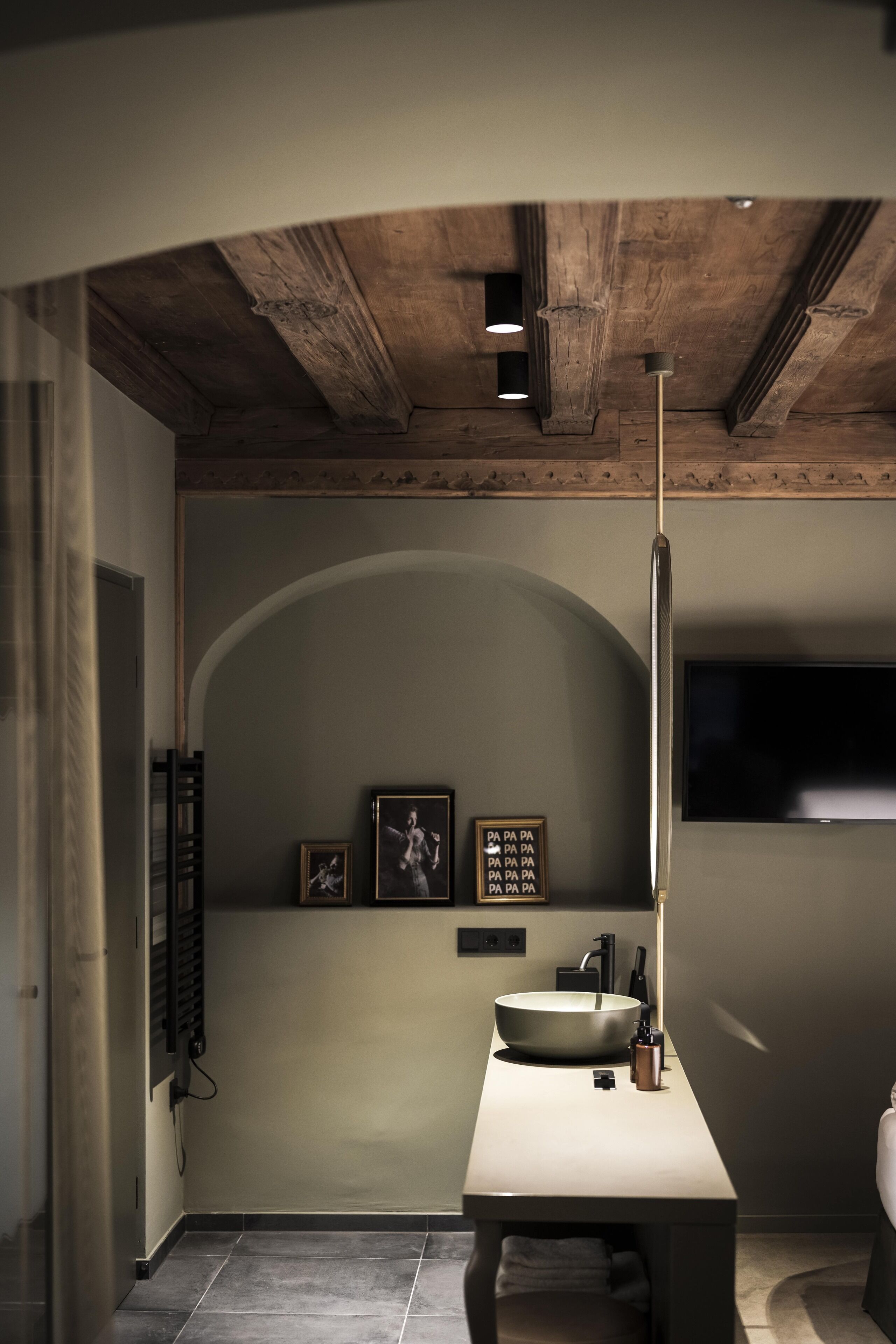 Un baño moderno con un lavamanos grande, un espejo y un televisor montado en la pared.