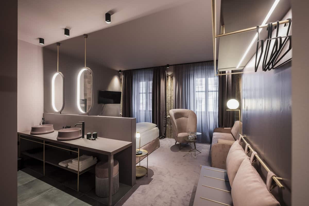 Habitació d'hotel moderna amb un llit gran, zona de seients, tocador amb mirall i escriptori.