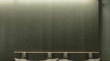 A bed with two pillows and a wooden headboard against a dark wall.