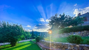 A stone wall with a grassy area and trees. - Poggio Cennina Resort (Bucine)