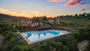 A pool area with lounge chairs and a stone building in the background. - Poggio Cennina Resort (Bucine)