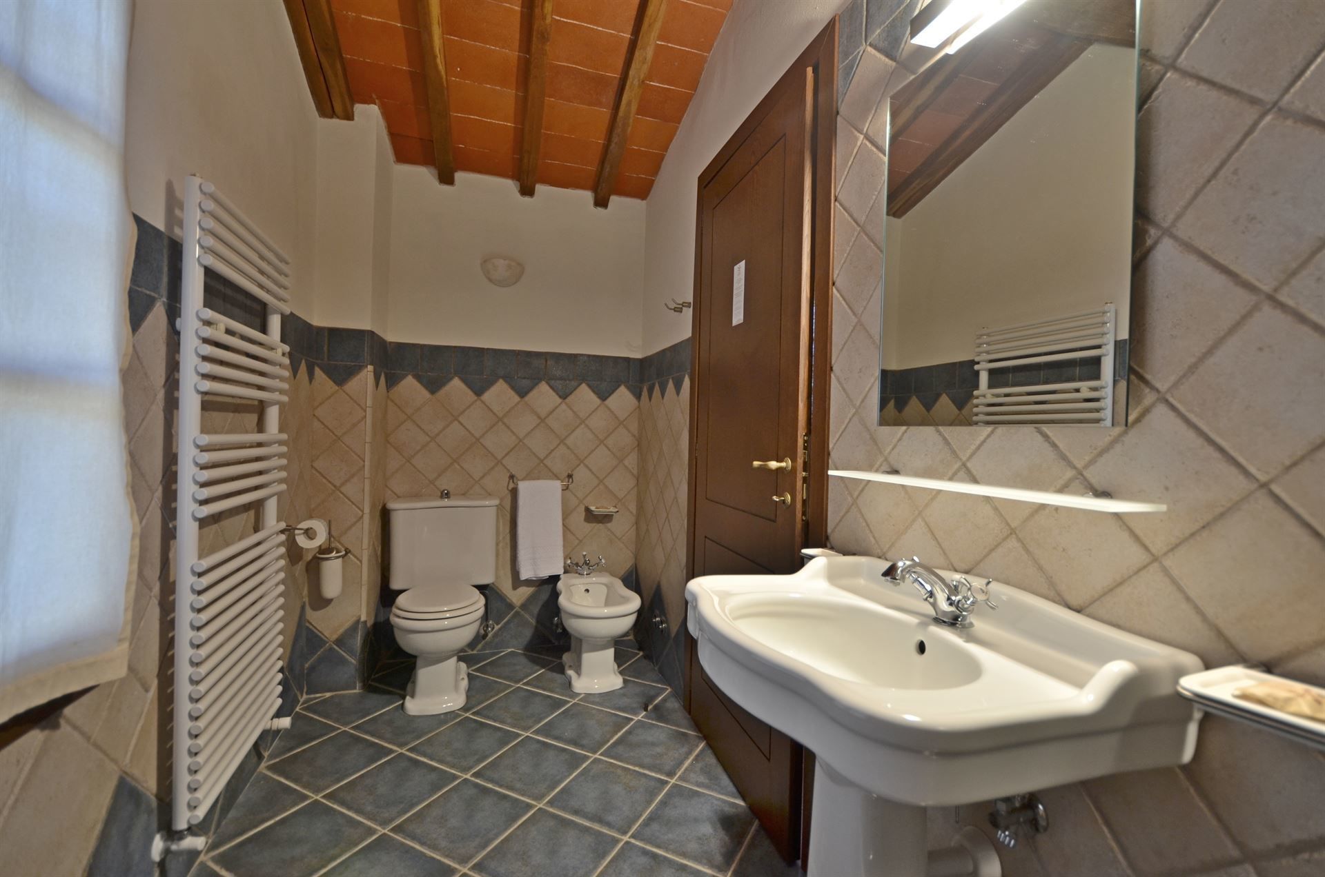 A bathroom with a sink, two toilets, and a mirror.