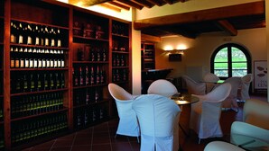 A wine cellar with wooden shelves and a table with chairs. - Poggio Cennina Resort (Bucine)