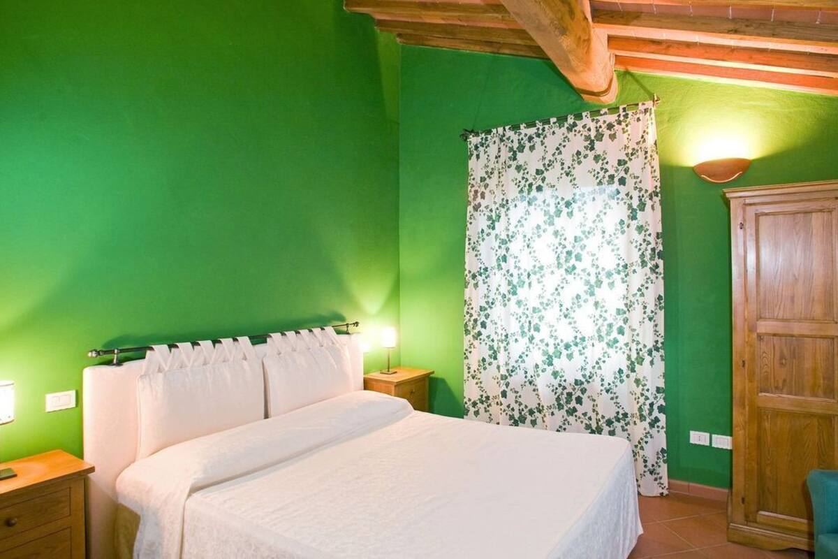 A bedroom with a bed, nightstands, a wooden wardrobe, and a green wall.