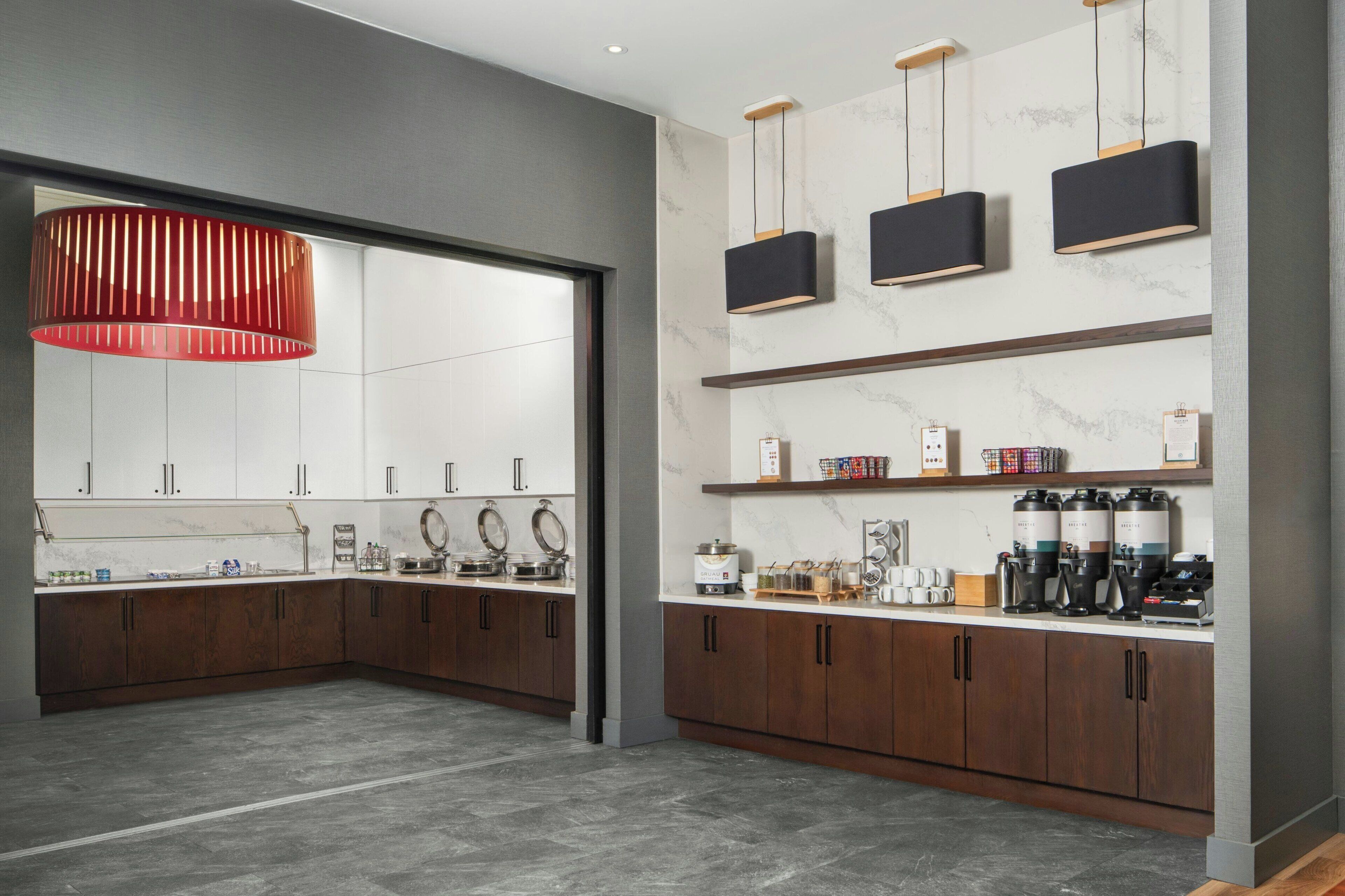 Una cocina moderna con armarios de madera oscura, salpicadero de mármol y una lámpara colgante roja.