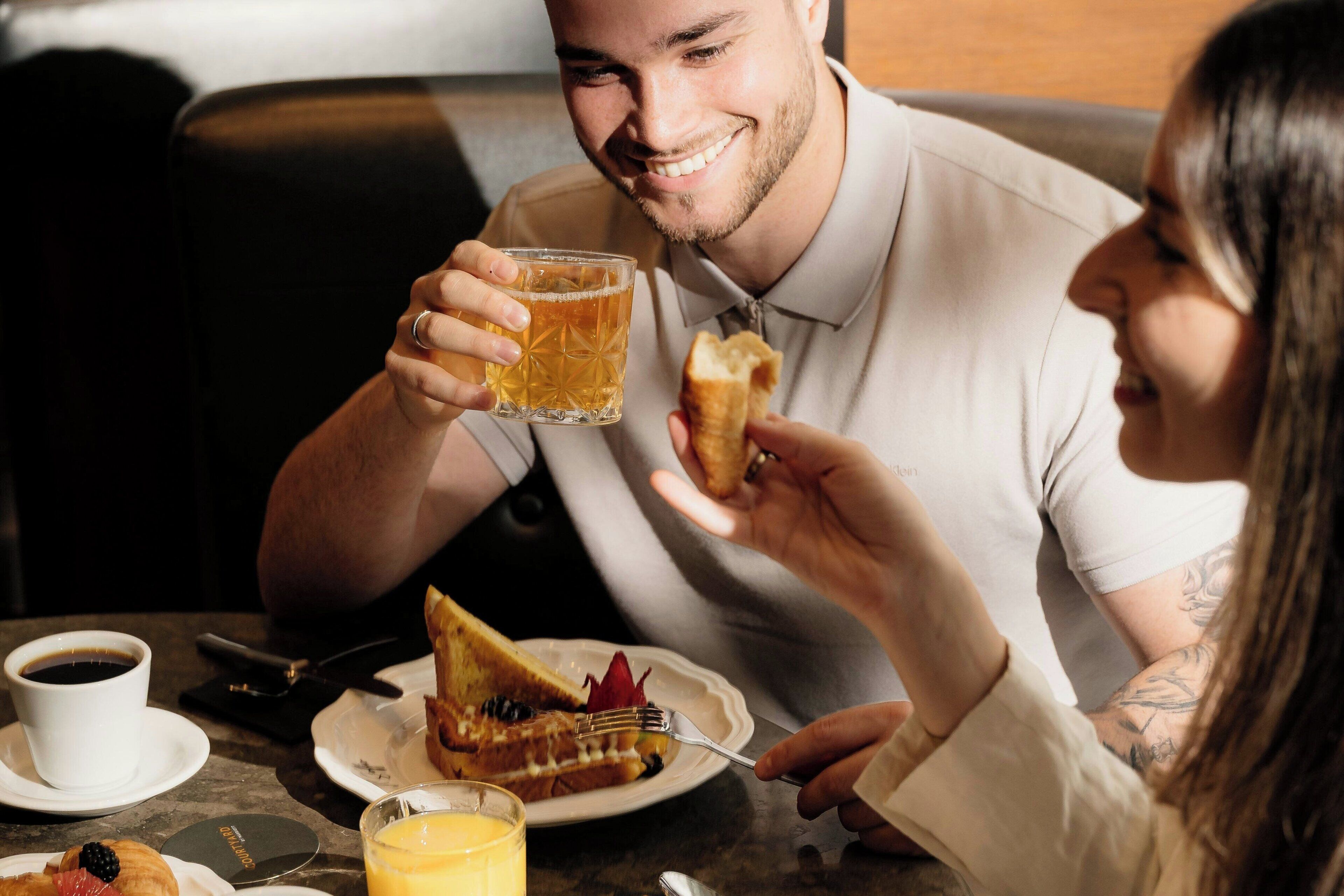 Ein Esstisch mit Tellern voller Essen, einem Glas Saft und einer Tasse Kaffee.