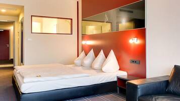 Een moderne hotelkamer met een bed, een tafeltje, een bank en een spiegel.