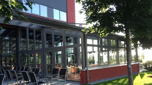 A modern building with large glass windows and outdoor seating.