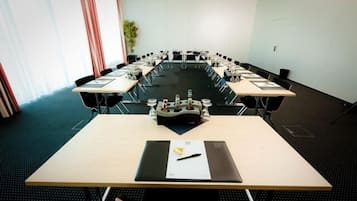 Uma sala de conferências com uma mesa comprida, cadeiras e um projetor.