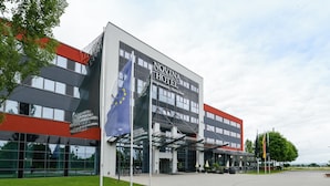 A modern hotel with a glass facade, a prominent sign, and a covered entrance area.
