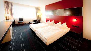 A hotel room with a large bed, a desk, and a chair.