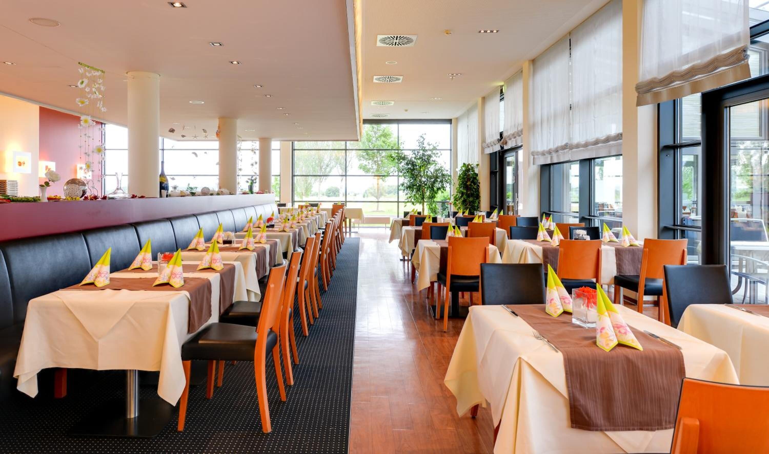 Un restaurant amb taules llargues, cadires i una zona de bar.