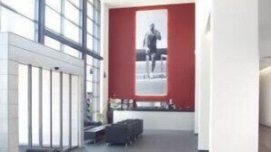 A modern lobby with black leather sofas, a red accent wall, and a large window.