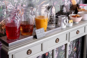 Una colazione a buffet con diverse bevande e un cartello che indica succo d'arancia, succo di mela e succo di mirtillo.