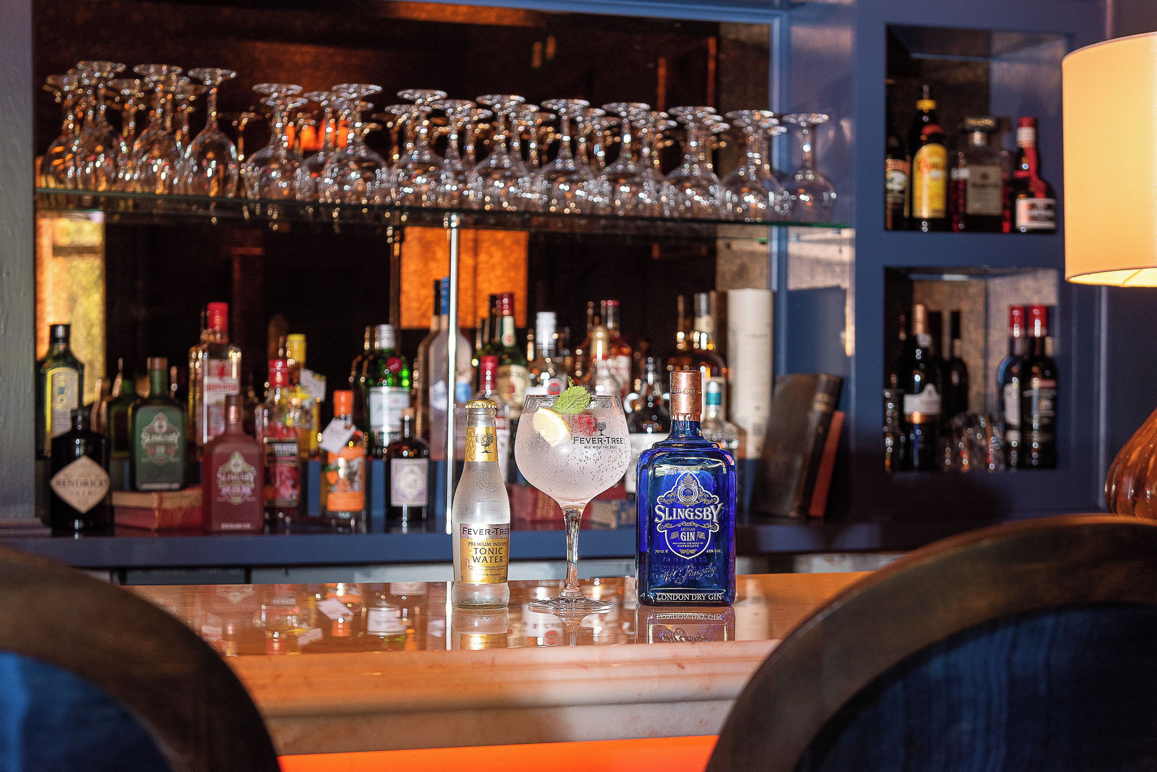 A bar area with various bottles and glasses, including a bottle of Slingsby gin and a glass with a lemon slice.