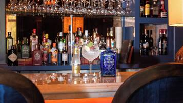 A bar area with various bottles and glasses, including a bottle of Slingsby gin and a glass with a lemon slice.