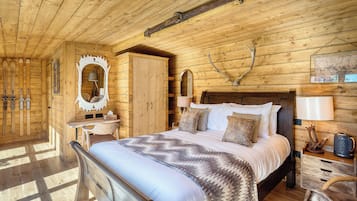 Ein Holzblockhaus-Interieur mit einem Bett, einer Kommode, einem Spiegel und Skiern an der Wand.
