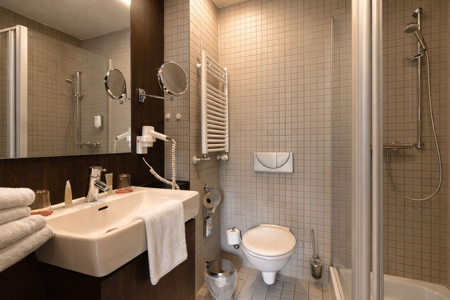 Un bagno moderno con lavandino, specchio, porta asciugamani, water, bidet e doccia.