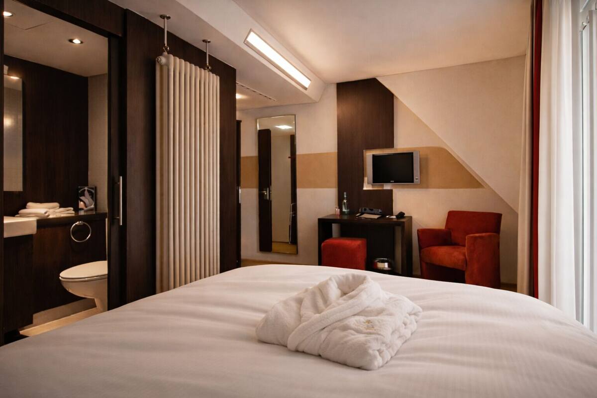 A hotel room with a bed, a TV, a desk, and a chair.