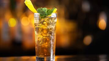 Un grand verre contenant une tranche de citron et quelques feuilles de menthe, rempli d’un liquide transparent et de glaçons.