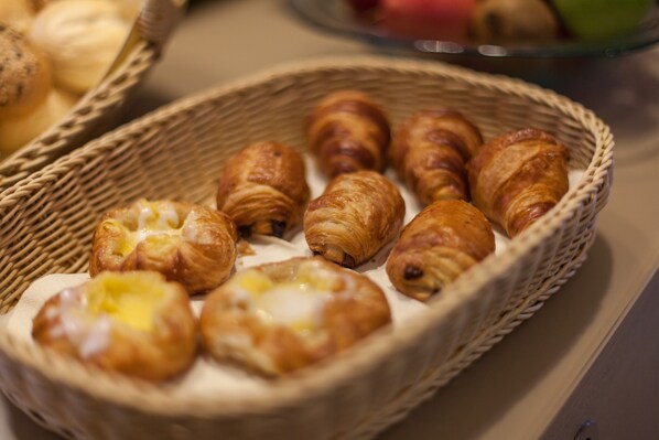 A basket of assorted pastries, including croissants and filled pastries, on a table. - Hotel Strijewski (Wolfsburg)