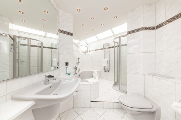 Un baño moderno con un lavamanos grande, una bañera, un inodoro y una ducha con mampara de vidrio.