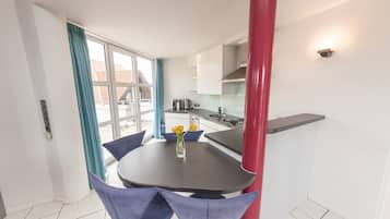 A modern kitchen with white cabinets, a black countertop, and a red pillar.