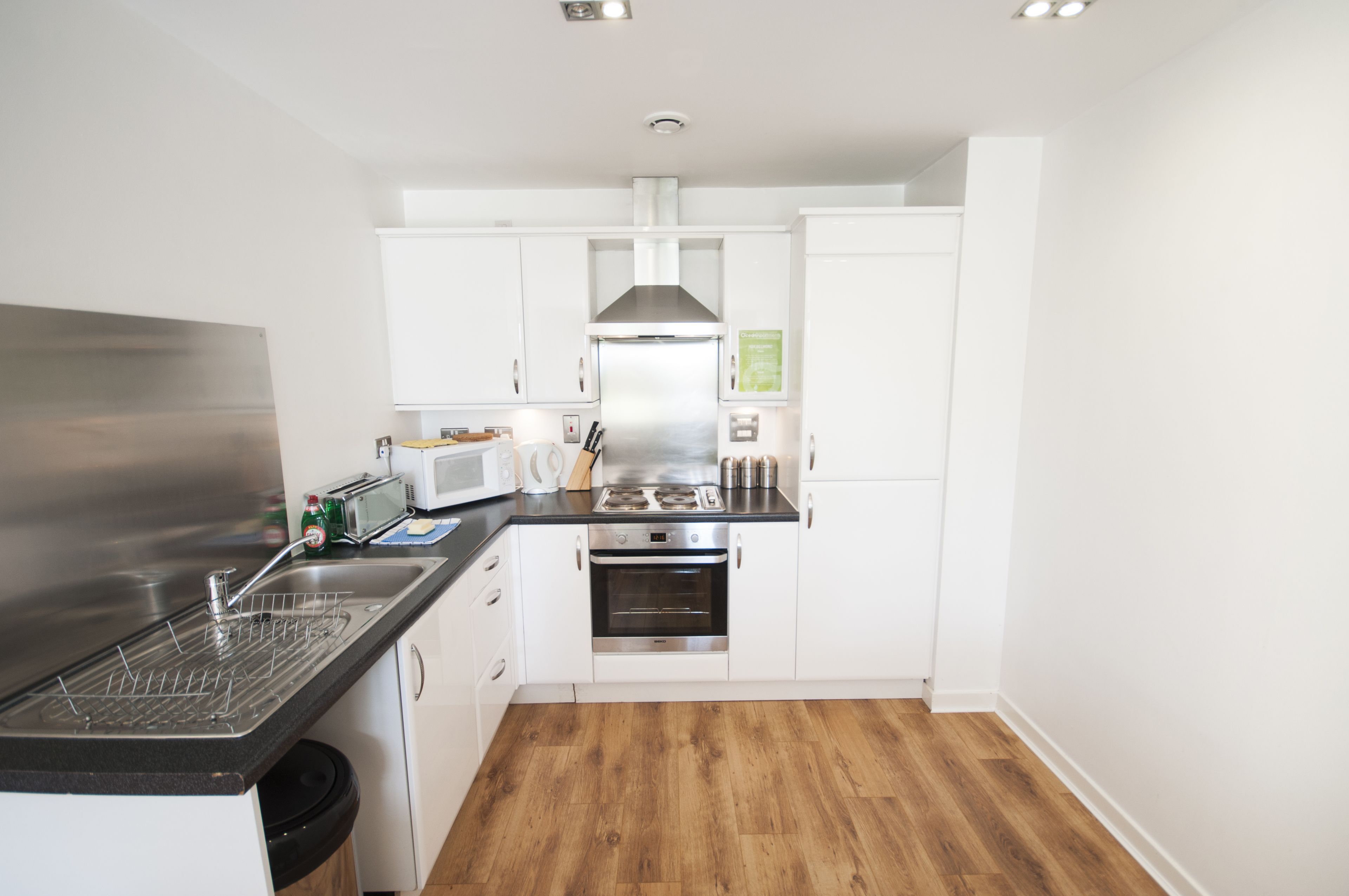 A compact kitchen with white cabinets, a stainless steel range, a microwave, and a dishwasher.