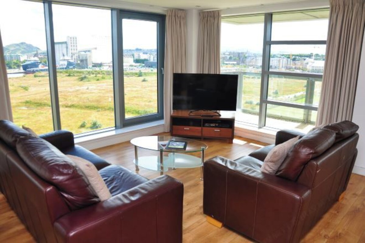 A modern living room with leather sofas, a TV, and a glass coffee table.