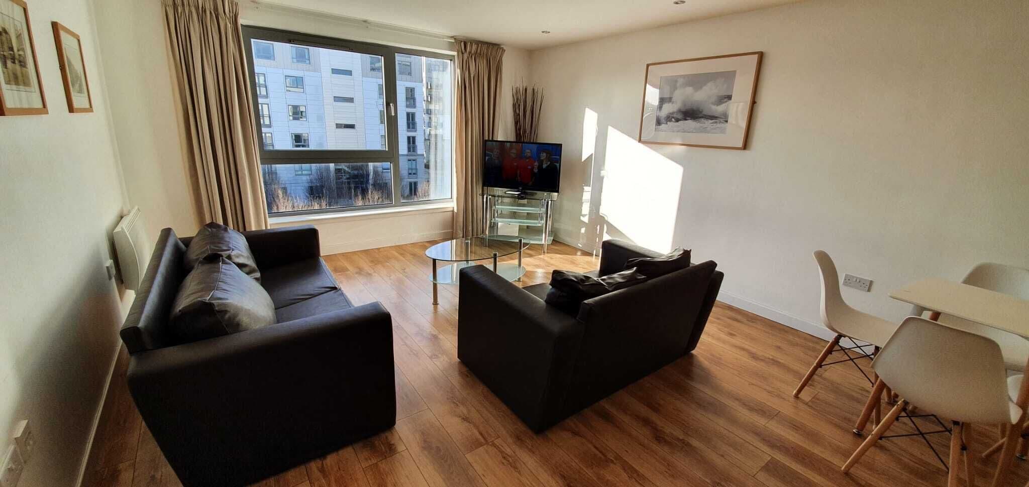 A modern living room with a sofa, a coffee table, and a TV.
