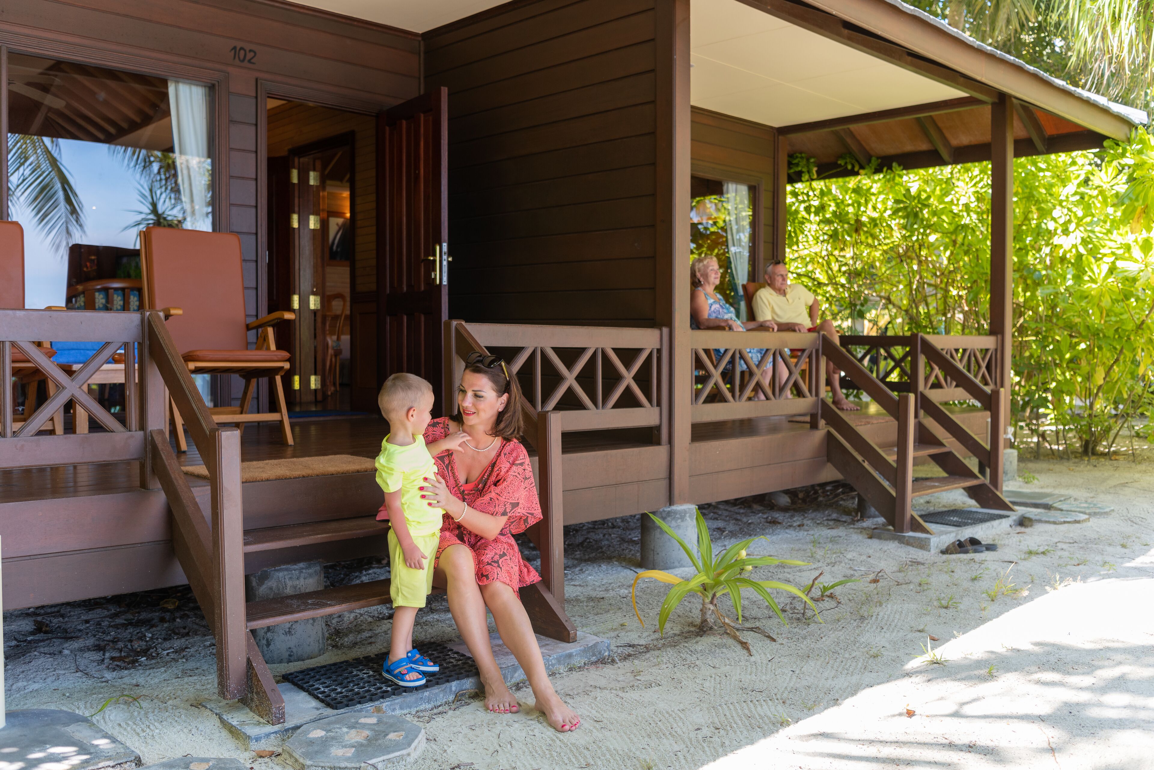 A wooden building with a porch and steps leading to a sandy area.